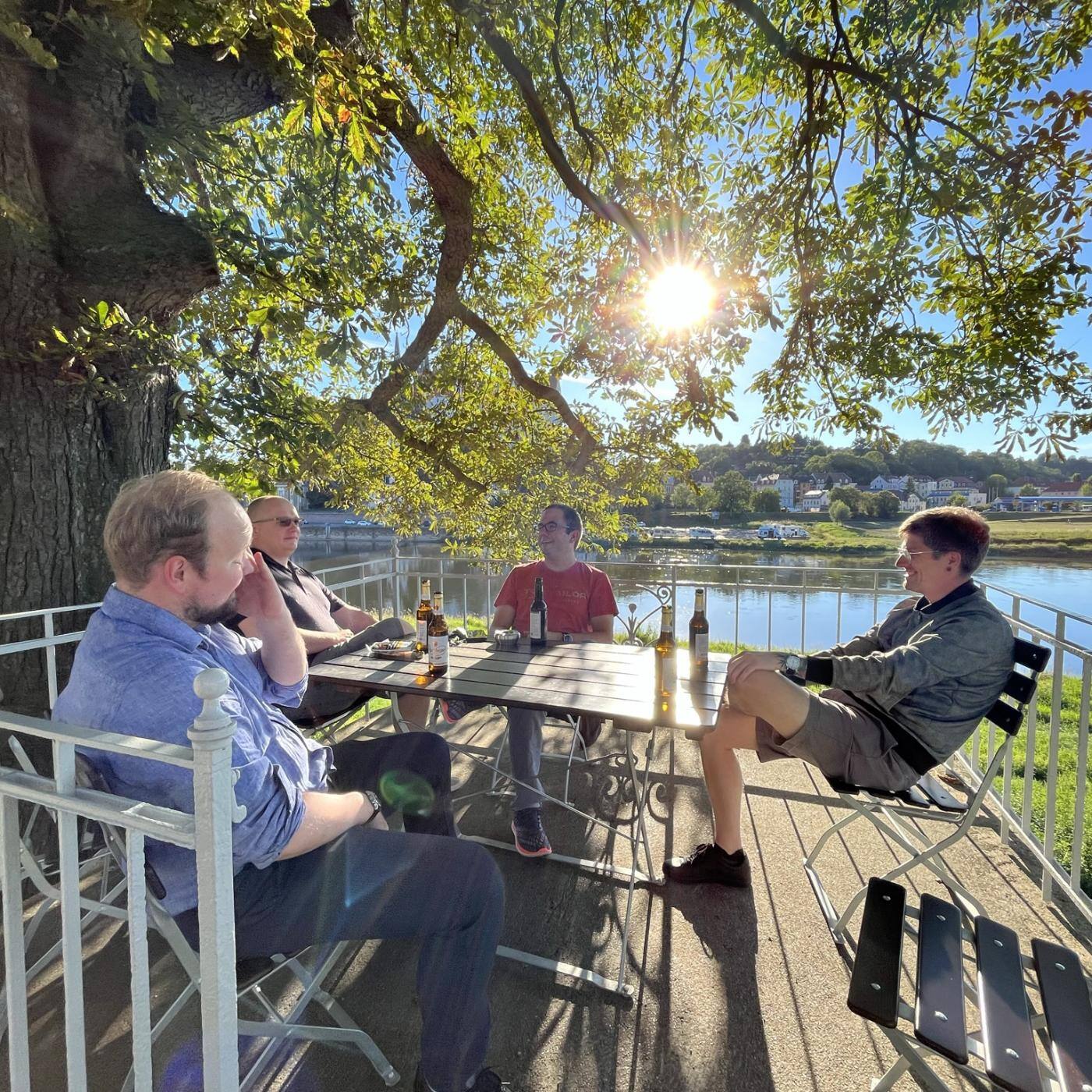 group of men sitting in the sun with beer